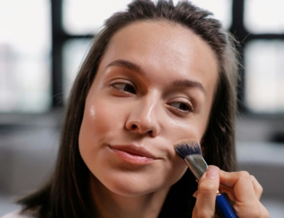 Mlada žena nanosi tekući puder kistom za šminku