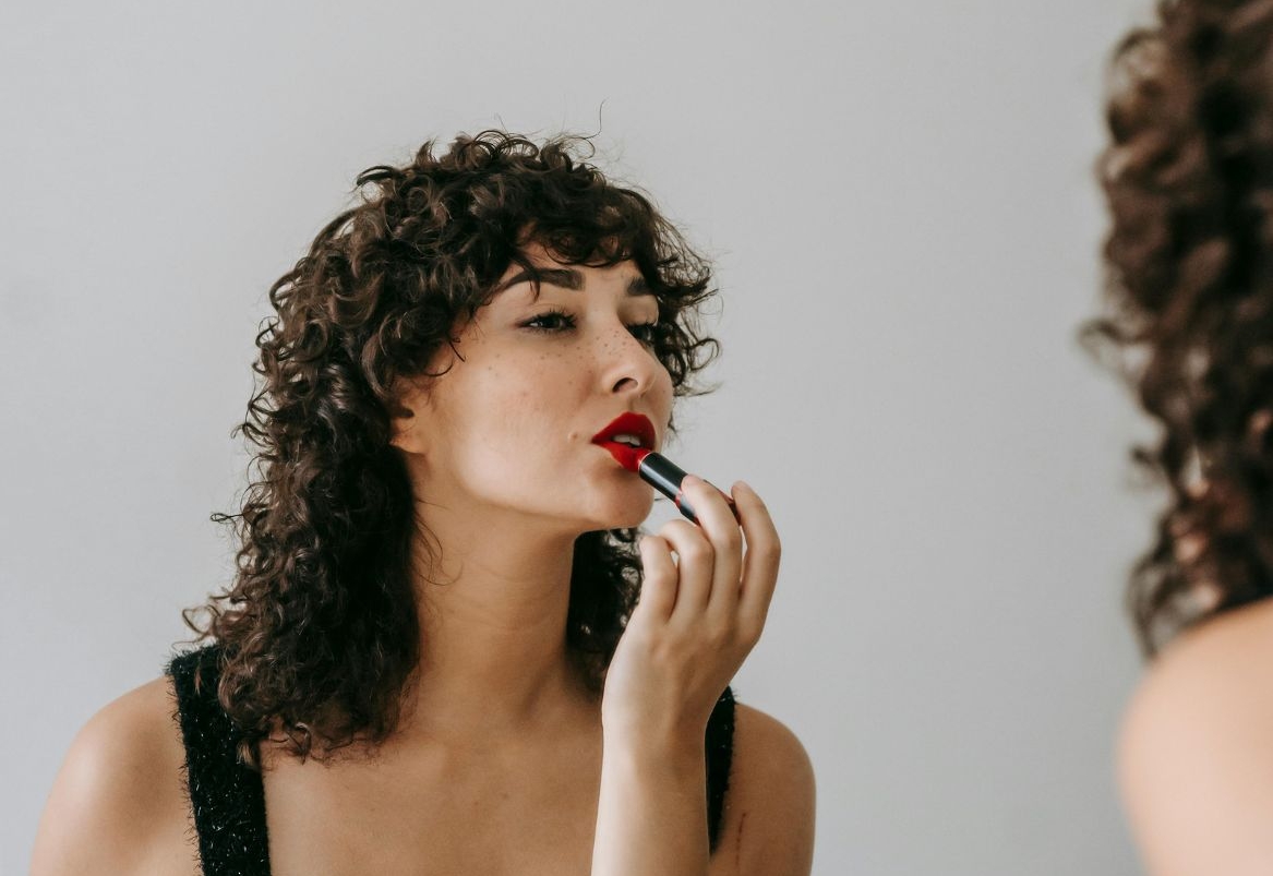 Žena u ogledalu nanosi crveni ruž