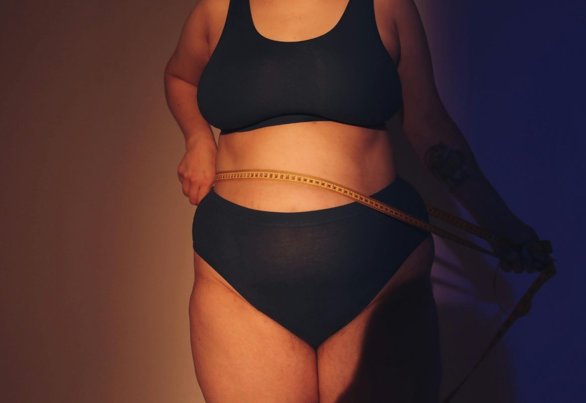 Žena prekomjerne težine mjeri opseg struka