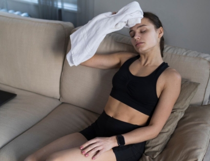 Žena koja drži ručnik na čelu uslijed znojenja