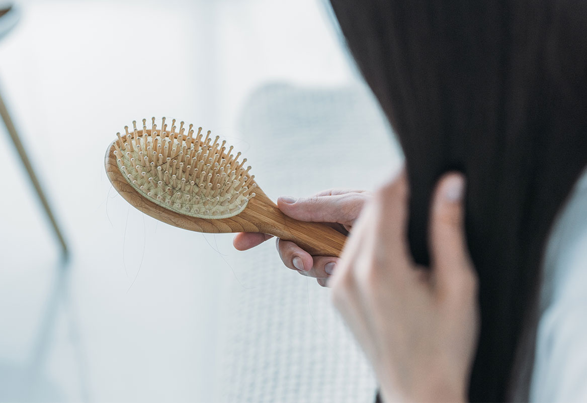 Žena drži četku za kosu s vidljivim otpalim vlasima